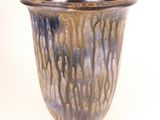 a blue and brown vase sitting on a white surface
