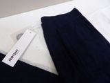 a white tag on a black pants on a white table
