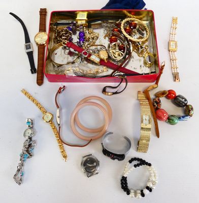 une boîte rouge remplie de bijoux variés, posée sur une surface blanche
