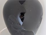 a black vase with a bird on it on a table