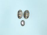 two pieces of jewelry on a blue surface with a white background