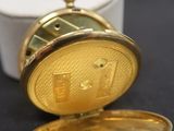 une petite montre de poche en or posée sur une table