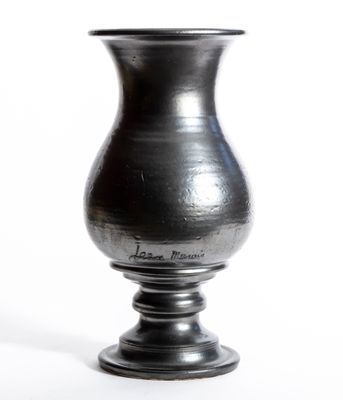 un vase noir posé sur une surface blanche