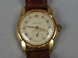 a gold wrist watch with a brown leather strap