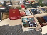 de nombreux livres rangés dans des cartons posés par terre