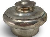 an old silver pot with a lid sitting on a white surface