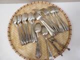 a lot of silver spoons and forks on a wicker tray