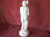 a white statue of a woman standing on a red cloth
