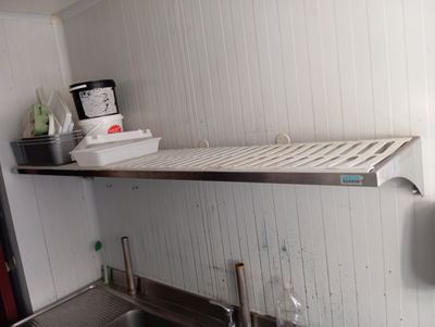 a sink in a kitchen with a shelf above it