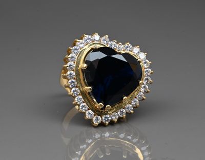 a close up of a blue sapphire and diamond ring on a reflective surface