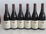 six bottles of red wine sit next to a glass of red wine