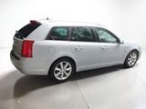 the back of a silver car is parked in a white room