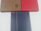 deux cahiers rouges et un cahier bleu posés sur une table blanche