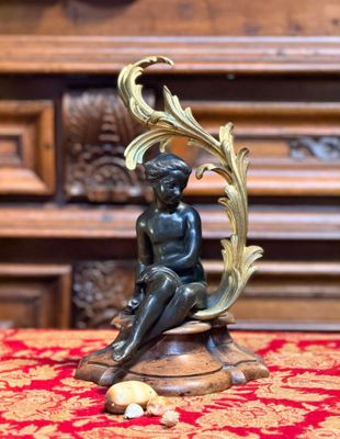 une statue en bronze représentant un garçon assis sur une table