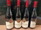 quatre bouteilles de vin rouge sont alignées sur un comptoir