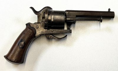 un vieux revolver avec une poignée en bois sur une surface blanche