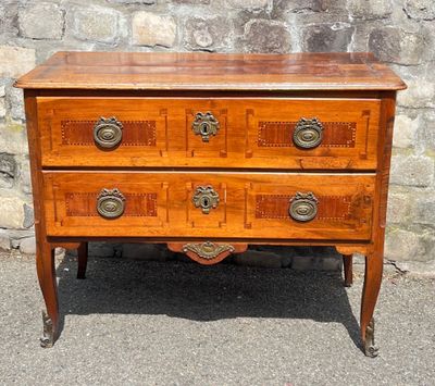 an old wooden chest of drawers sitting on top of a stone wall