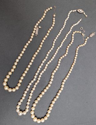 trois colliers de perles et une paire de boucles d'oreilles posés sur une table