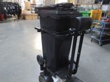 a black trash can sitting on top of a dolly in a warehouse
