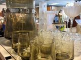 bottles and glasses on a counter in a restaurant with people in the background