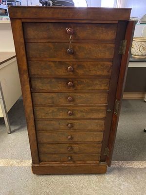 une vieille commode en bois dans une pièce où se trouve une chaise