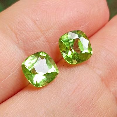 pair of green peridot gems on a person ' s finger