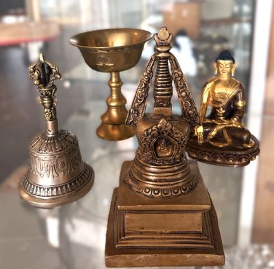 une table en verre sur laquelle sont posées trois statues en laiton et un bol