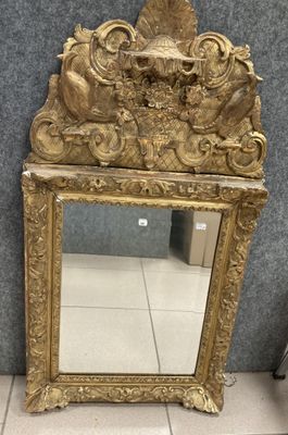 miroir avec un cadre doré et une décoration ouvragée sur le dessus