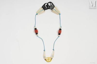 un gros plan d'un collier posé sur une surface blanche, muni d'un cordon noir
