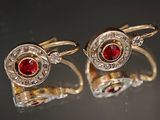 une paire de boutons de manchette en rubis et diamants posés sur une surface réfléchissante