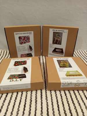 three boxes of assorted items sitting on a bed with a striped blanket