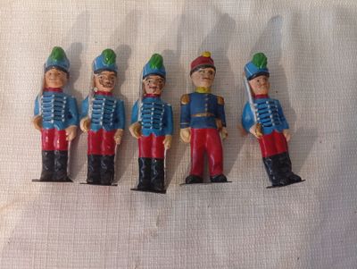 Quatre petits soldats sont alignés sur une surface blanche