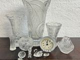 several pieces of glass sitting on top of a table next to a clock