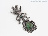 an image of a broochle with a green stone surrounded by diamonds