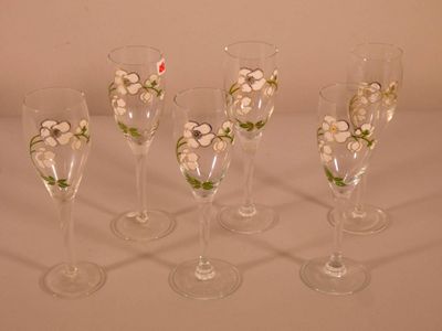 Quatre verres à vin décorés de fleurs sont alignés sur une table