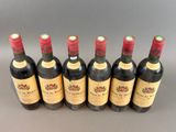 six bottles of wine are lined up in a row on a table