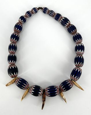 un collier bleu et blanc orné de pointes dorées sur fond blanc