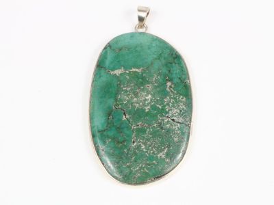 un gros plan d'un pendentif en pierre verte posé sur une surface blanche