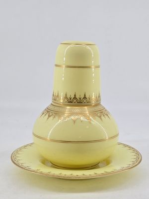 a yellow vase and saucer on a white table