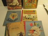 Plusieurs livres pour enfants sont posés sur une table, à côté d'une paire de ciseaux.