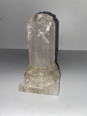 une pierre de quartz transparent posée sur une surface blanche