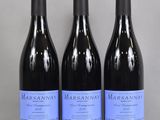 three bottles of wine are lined up on a glass table