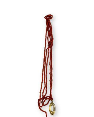 collier composé de perles rouges et d'un anneau doré sur fond blanc
