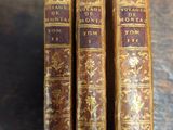 three old books sitting on top of a wooden table next to each other