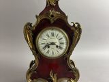 une petite horloge rouge surmontée d'un oiseau