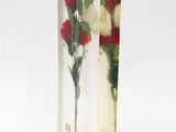 a clear vase with flowers inside of it on a white surface