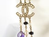 a close up of a necklace with pearls and a chandelier