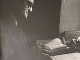 une vieille photo en noir et blanc représentant un homme assis à un bureau avec un livre