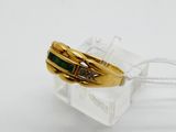 yellow gold ring with emerald and diamonds on a clear acrylic block