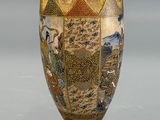a gold vase with a painting on it sitting on a table
